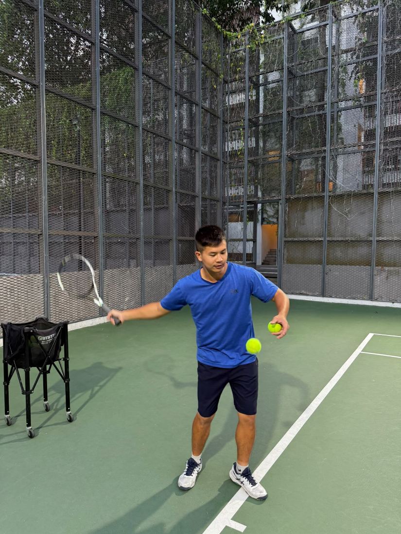 Coach Sherwin Foo courtside with a ball and racquet during an evening session
