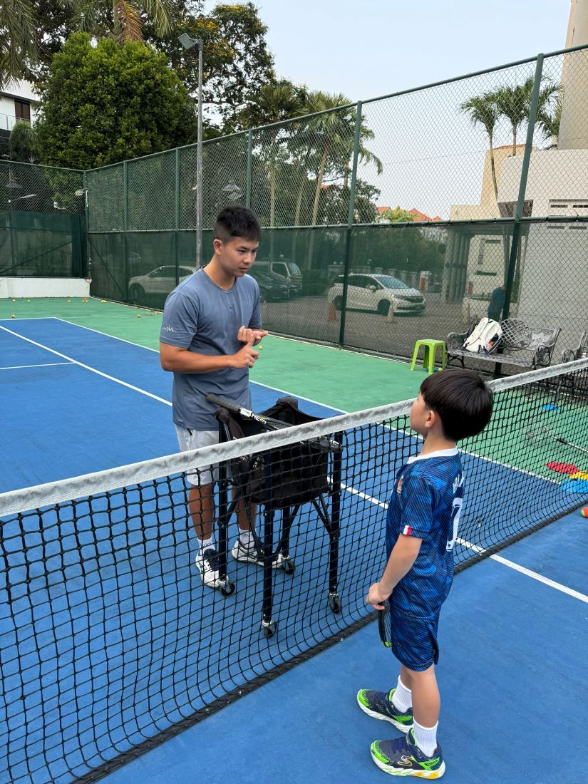 Sherwin Foo talking a junior through a point at the net