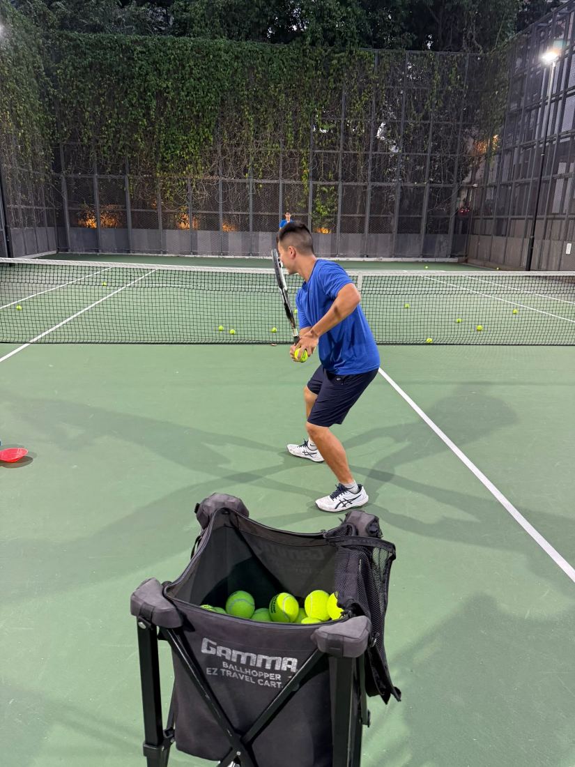 Sherwin Foo feeding from a ball basket during an evening session