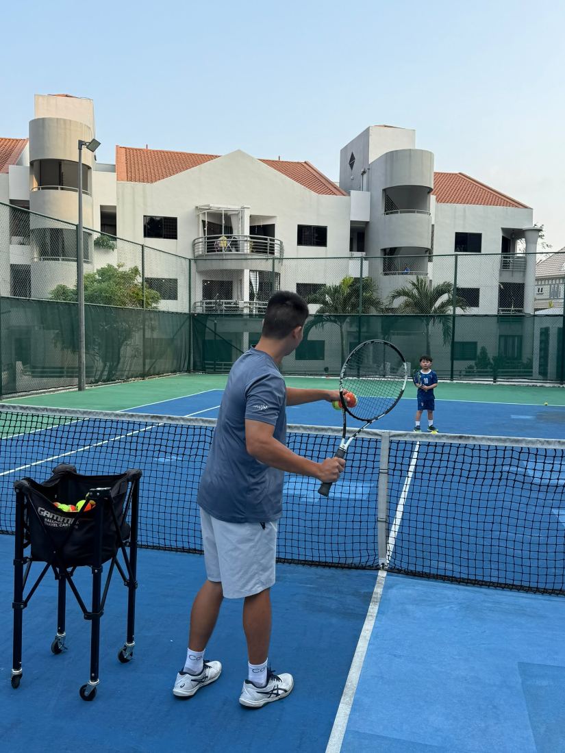 Sherwin Foo feeding balls to a young player during a private lesson