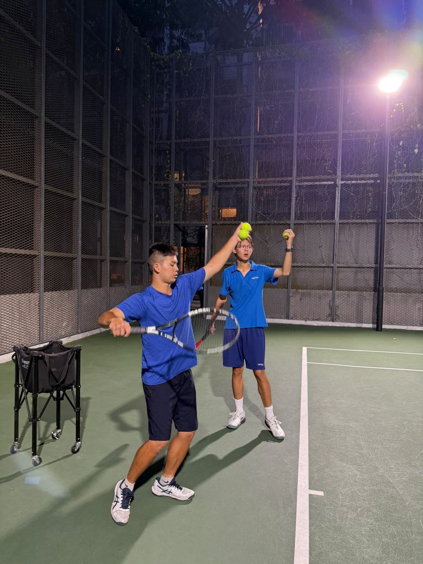 Sherwin Foo guiding a junior player’s grip and racquet position